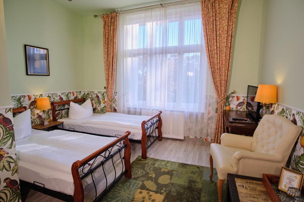 a bedroom with two beds and a chair and a window at Anno 1900 Hotel Babelsberg in Potsdam