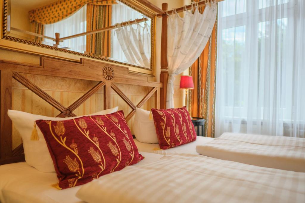 a hotel room with two beds and a mirror at Anno 1900 Hotel Babelsberg in Potsdam