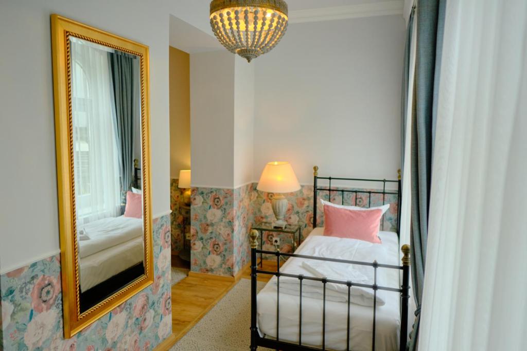 a bedroom with a mirror and a bed with pink pillows at Anno 1900 Hotel Babelsberg in Potsdam