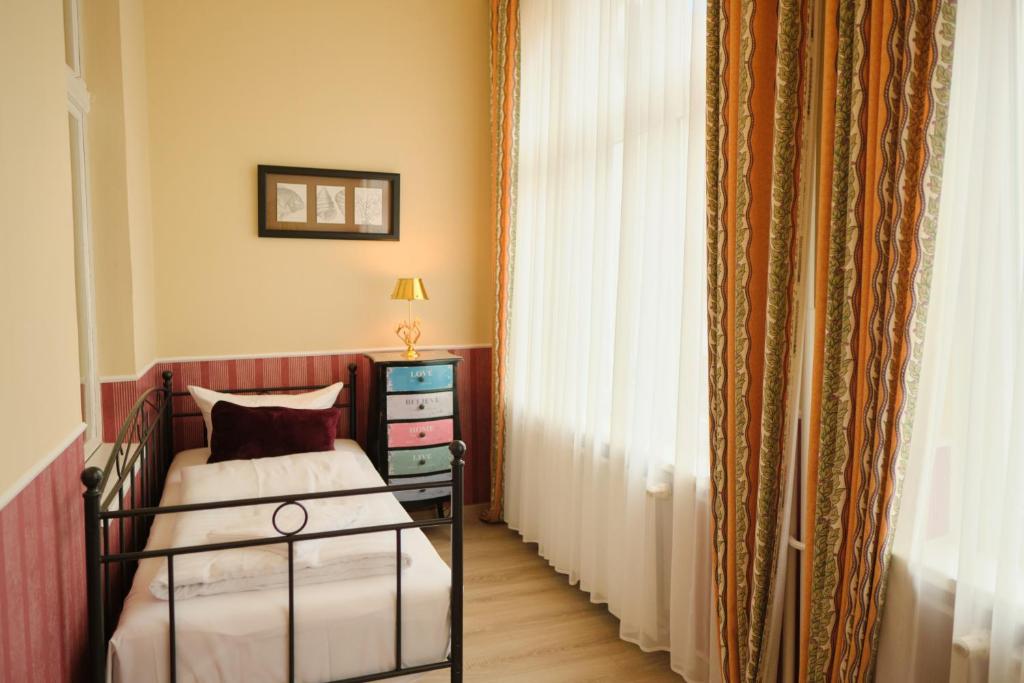 a bedroom with a bed and a dresser and a window at Anno 1900 Hotel Babelsberg in Potsdam