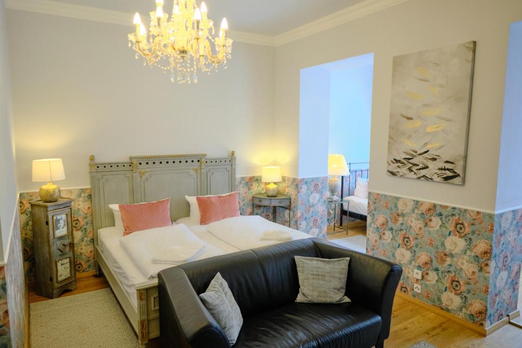 a bedroom with a bed and a couch and a chandelier at Anno 1900 Hotel Babelsberg in Potsdam