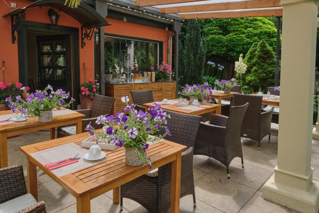 a patio with tables and chairs with purple flowers at Anno 1900 Hotel Babelsberg in Potsdam