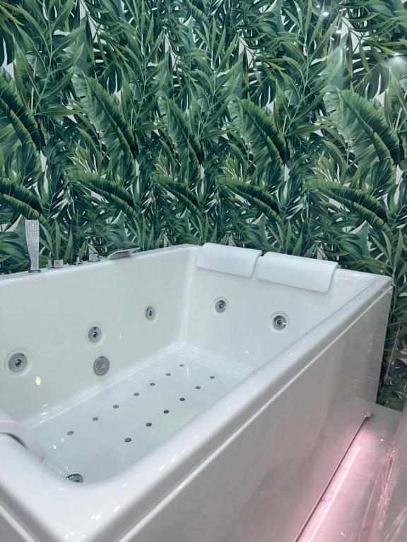 une baignoire blanche devant une plante verte dans l'établissement Suite La Vigna, à Catane