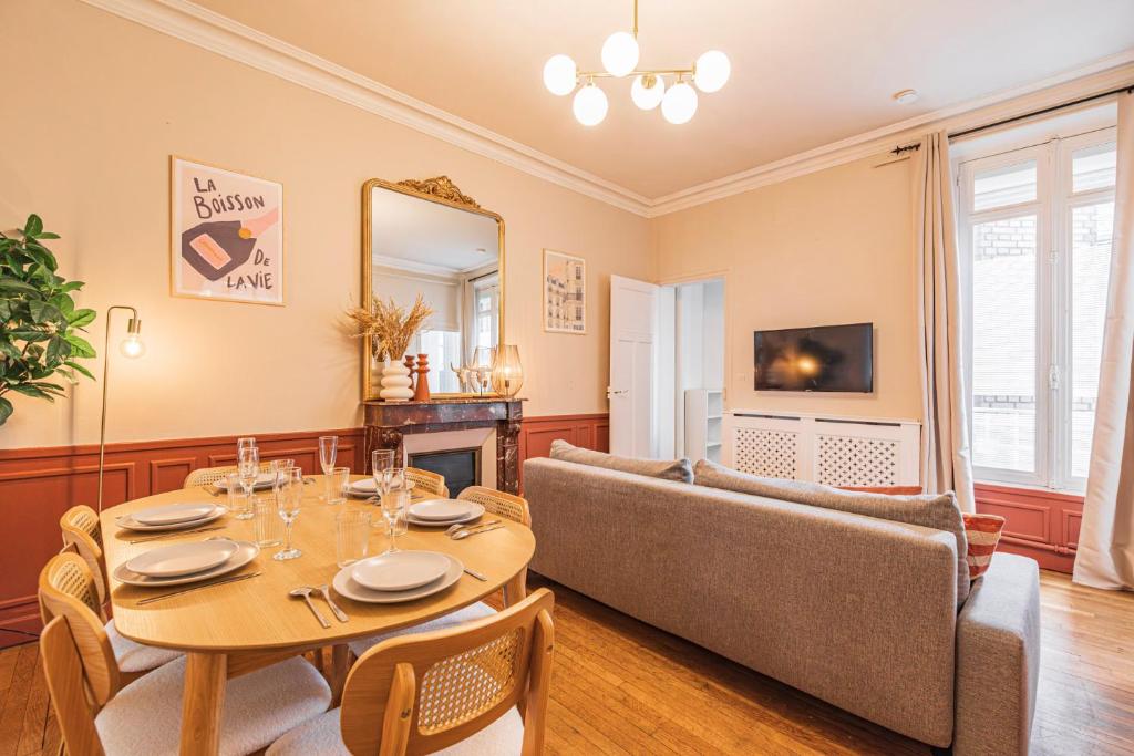 une salle à manger avec une table et un canapé dans l'établissement L'haussmannien - Spacieux 4 chambres - Centre - Gare, à Reims