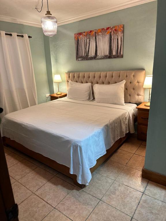 a bedroom with a large bed with white sheets at El Cayuco Restaurant Apart Hotel in Boca Chica