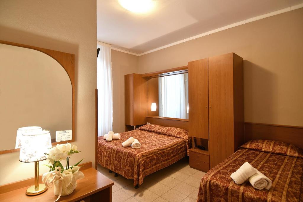 a hotel room with two beds and a mirror at Hotel Innocenti in Montecatini Terme