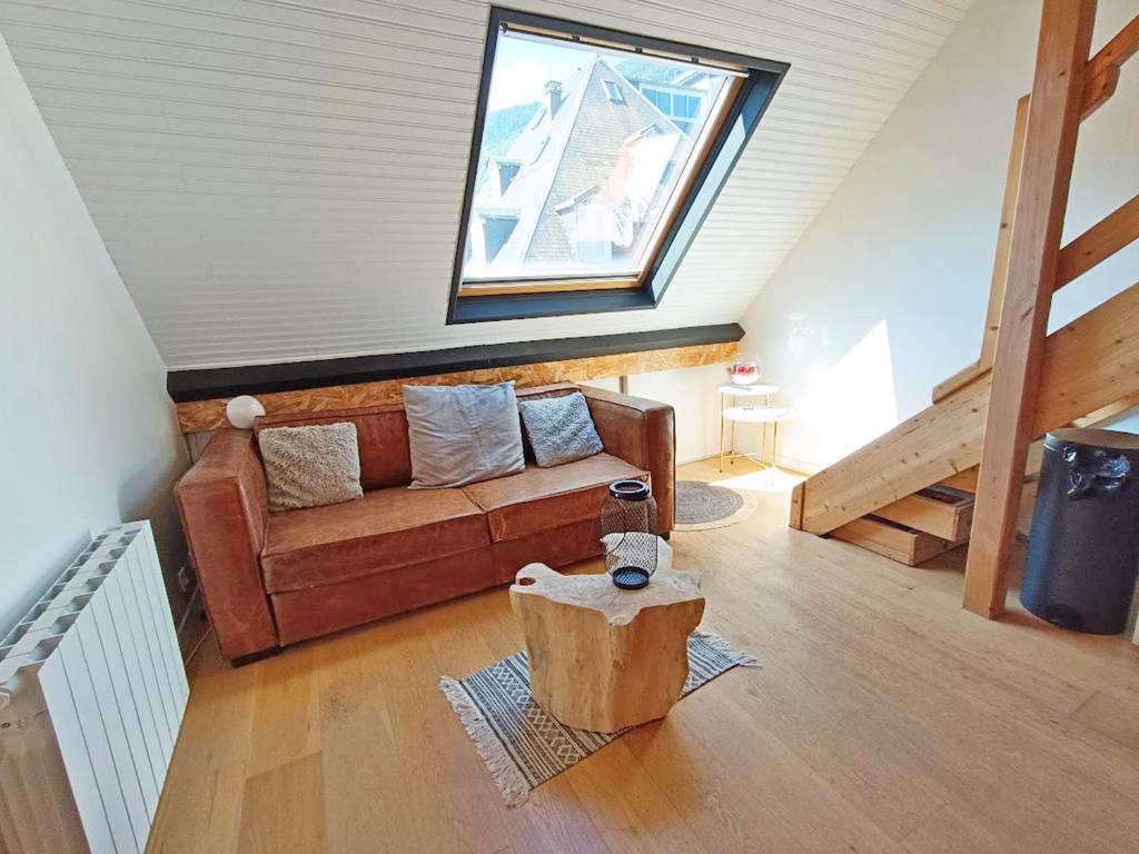 un salon avec un canapé et une fenêtre dans l'établissement Le nid de Juliette, T3 duplex, parking, cave, à Luchon