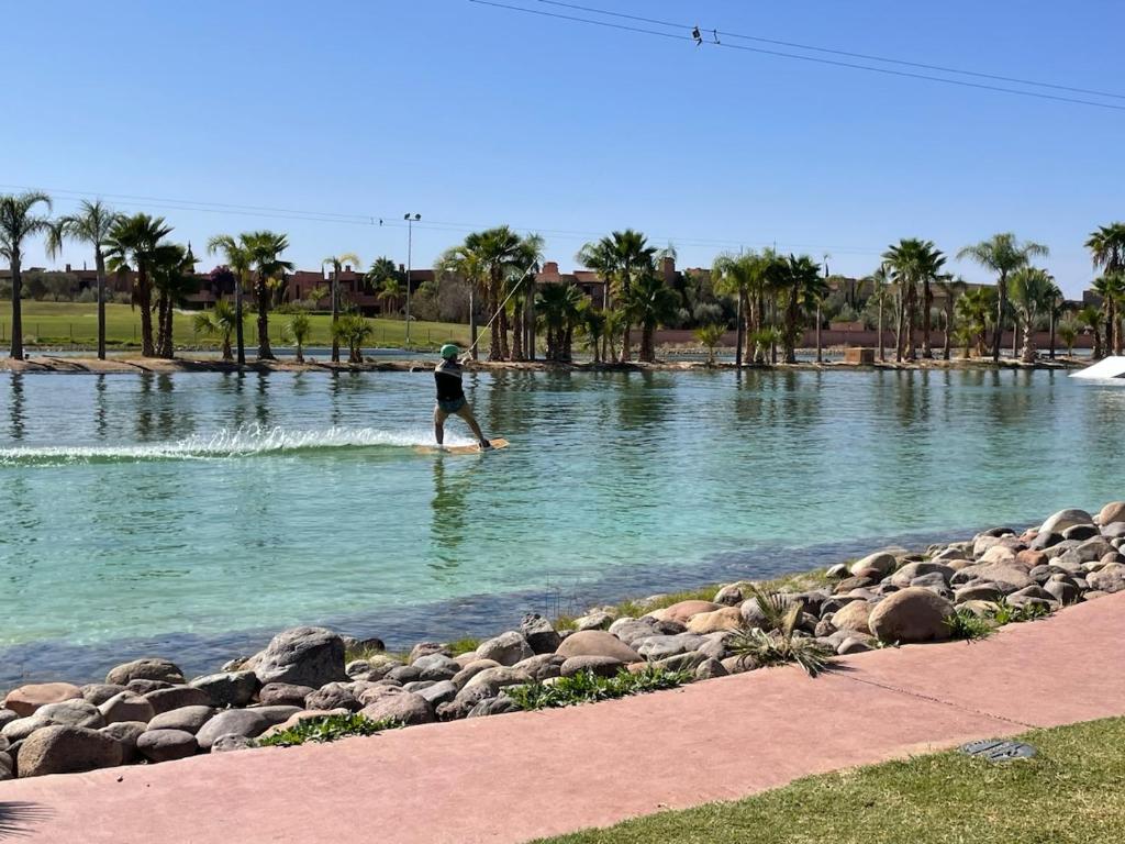 a person on a paddle board in the water at Villa confortable et familiale de 458 m2 avec piscine privée au cœur du domaine des jardins de lAtlas à Marrakech in Sraghna