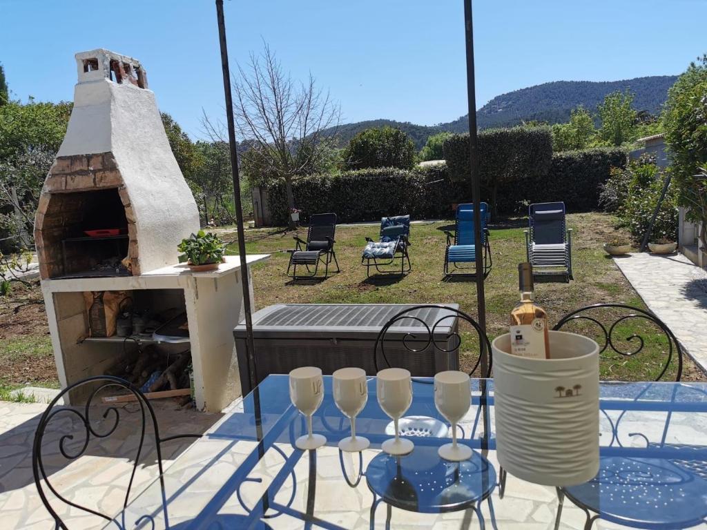 d'une terrasse avec une table, des chaises et un four à pizza. dans l'établissement Jolie maison avec jardin, à Hyères