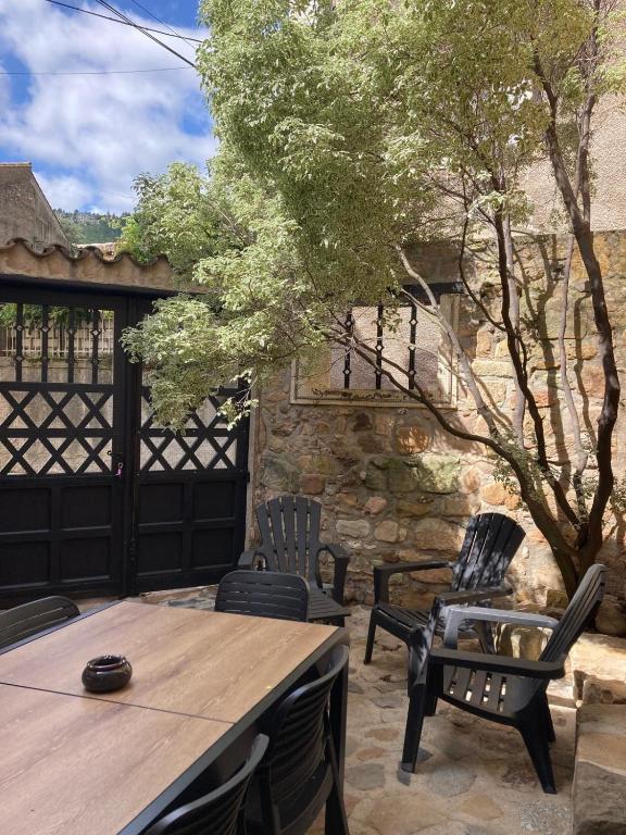 d'une terrasse avec une table, des chaises et un arbre. dans l'établissement Maison 2 chambres avec cour intérieure, à Alet-les-Bains