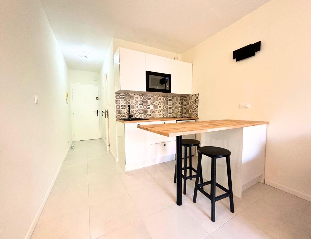 une cuisine avec un comptoir et deux tabourets de bar dans l'établissement Studio vue mer - Clim, Piscine & restaurant, à Nice