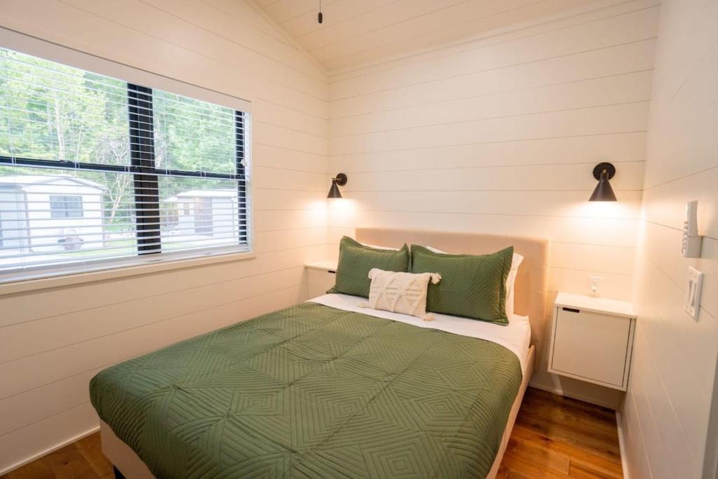 ein kleines Schlafzimmer mit einem grünen Bett und einem Fenster in der Unterkunft Creekside Modern Tiny Home - Firepit - Racoon Cabin in Gatlinburg