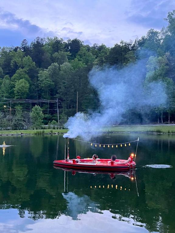 ein rotes Boot auf einem See mit einem Schornstein in der Unterkunft Creekside Modern Tiny Home - Firepit - Racoon Cabin in Gatlinburg