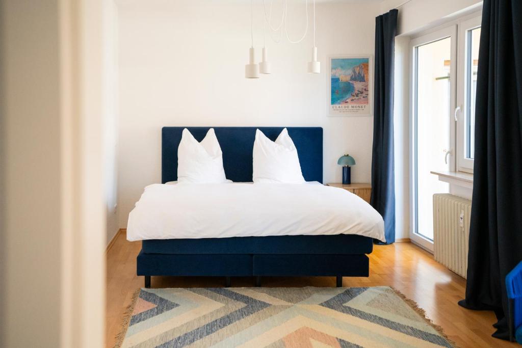 a bedroom with a blue and white bed with white pillows at Blauwal - W14, Zentral in Bahnhofsnähe, Balkon, Küche in Ulm