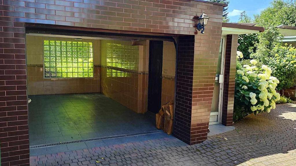 a brick building with an open door with a patio at Puszczykowska willa in Puszczykowo
