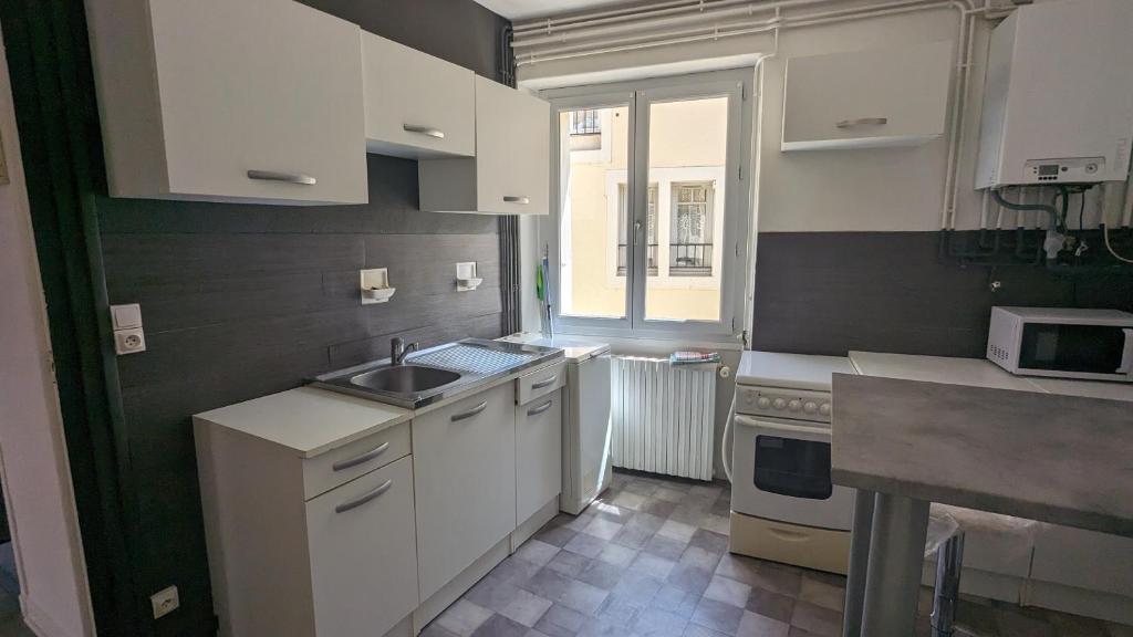 a kitchen with white cabinets and a sink and a window at appartement rénové-équipé en centre-ville in Le Puy en Velay