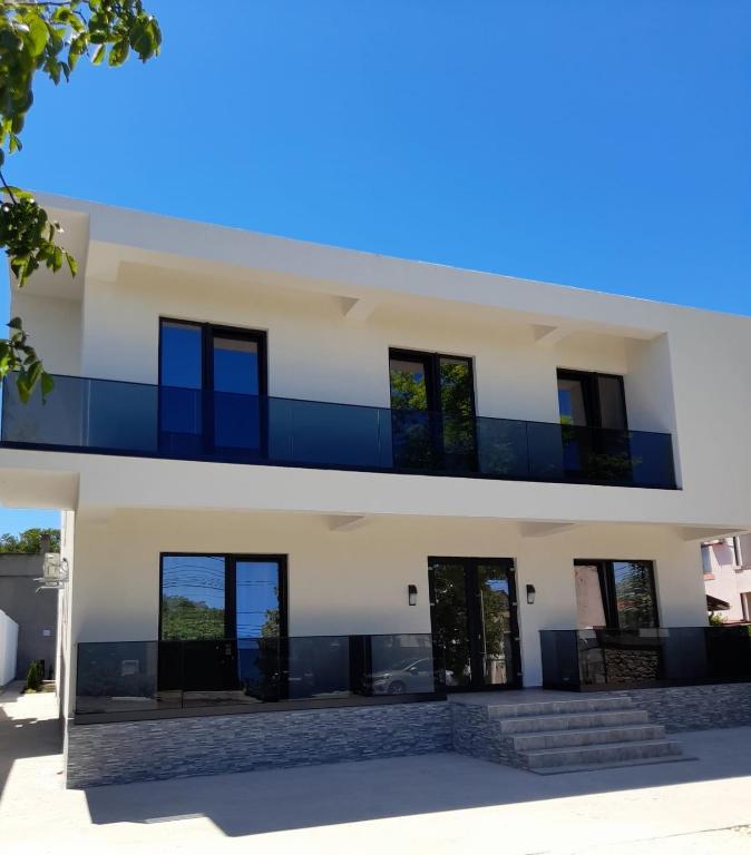 a white house with blue windows at Vila SEA VIBES in Eforie Sud