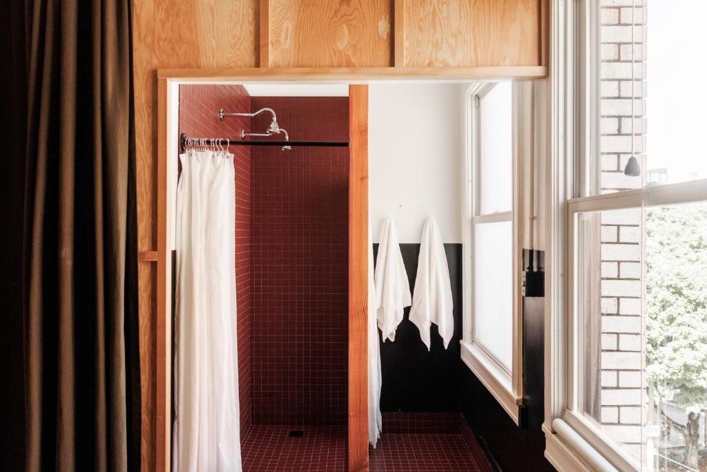 a bathroom with a shower with a white shower curtain at The Clyde Hotel Portland by Kasa Living in Portland