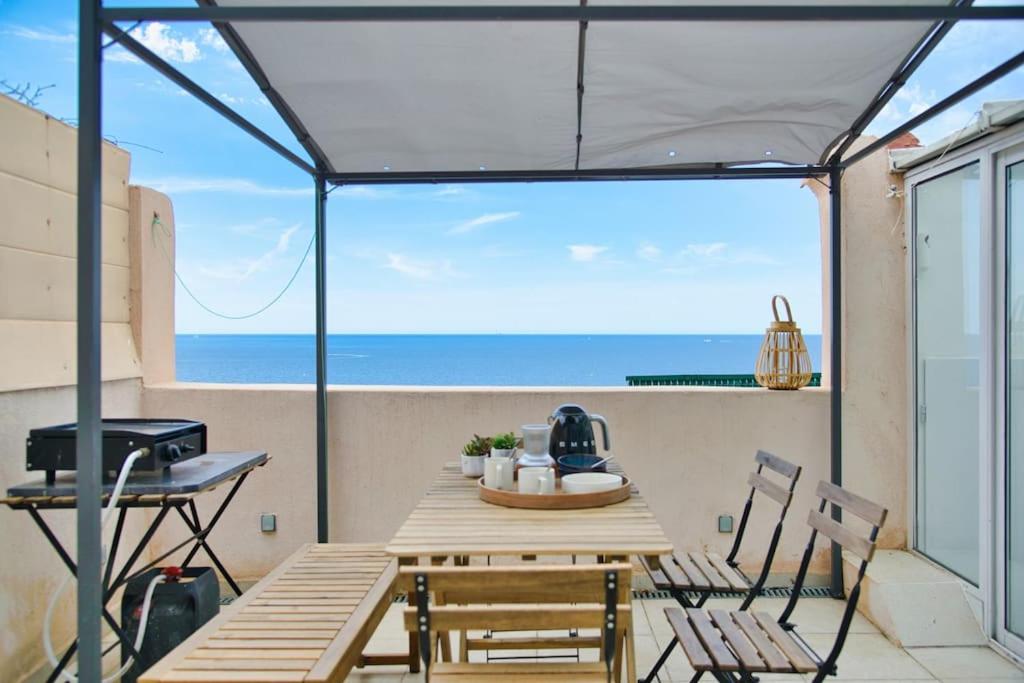 une table et des chaises sur un balcon avec vue sur l'océan dans l'établissement Coquet appartement en bord de mer et corniche, à Marseille