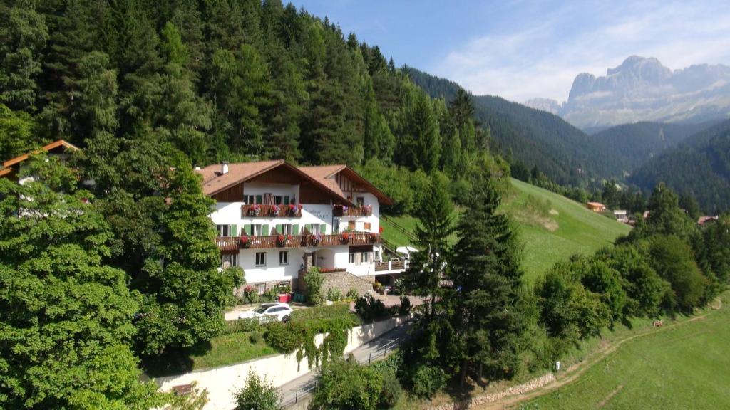a large house in the middle of a mountain at Hotel Berghaus Rosengarten in Nova Levante
