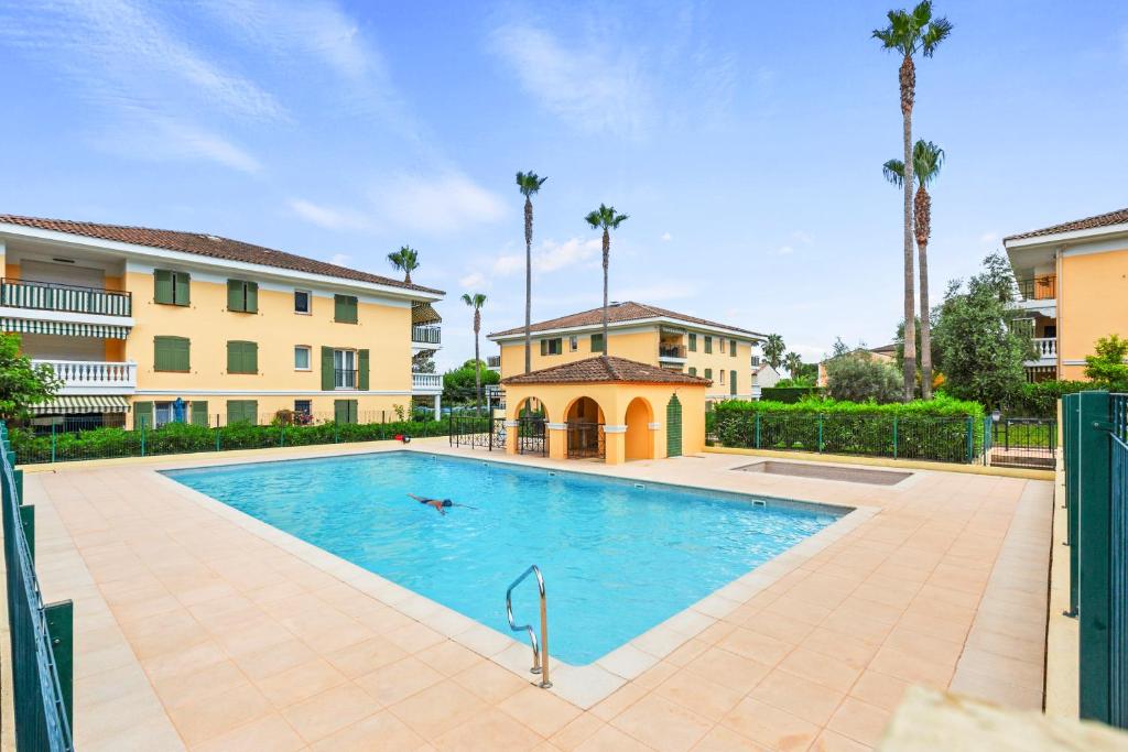 une piscine devant un immeuble avec des palmiers dans l'établissement Haut Standing /Mandelieu - Cannes, à Mandelieu-la-Napoule