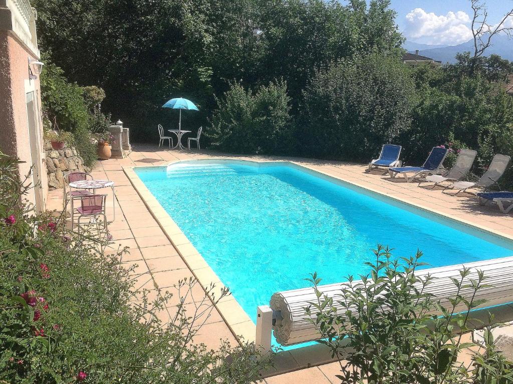 a swimming pool with chairs and a table and an umbrella at Studio indépendant dans villa avec piscine à Gap in Gap
