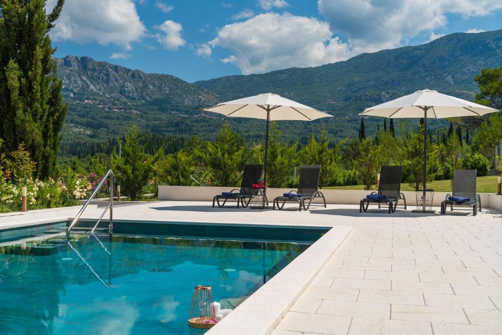 een zwembad met 2 stoelen en parasols bij House Terra Madre in Gruda