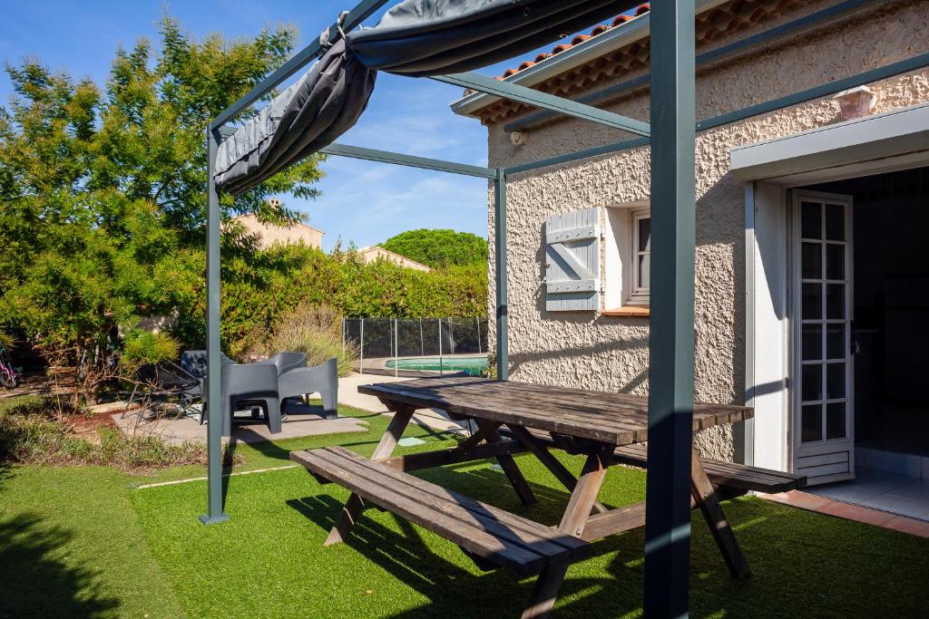 Una mesa de picnic y una sombrilla en un patio. en Maison Roxane, en Curet