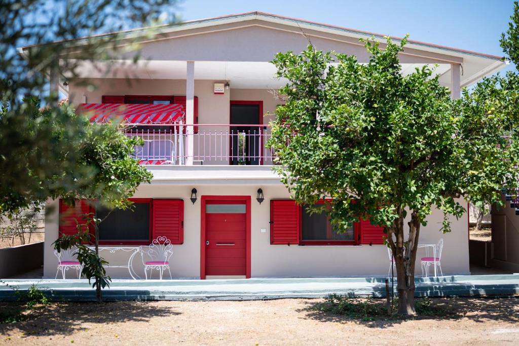 a white house with red doors and a tree at Oregano peaceful complex in Porto Rafti