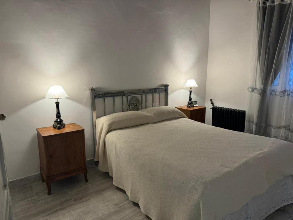 a bedroom with a bed and two night stands with lamps at Las Magnolias House and Garden in Virrey Toledo