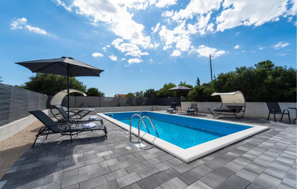 - Piscina con 2 sillas, sombrilla y sombrilla en Gorgeous Home In Polaca, en Polača
