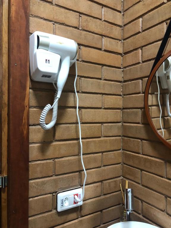 a hair dryer is attached to a brick wall at Refúgio Rodreipe in São Bento do Sapucaí