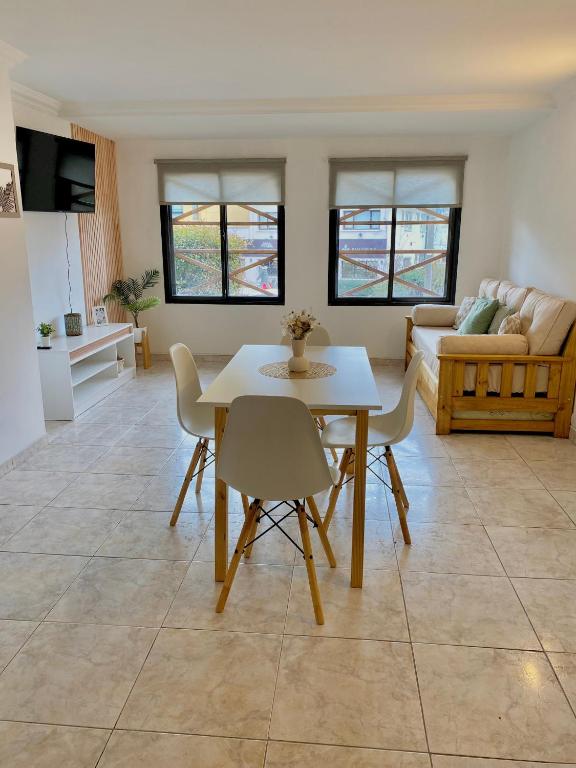 Una sala de estar con una mesa y sillas blancas. en Departamento Céntrico Belgrano 2, en San Carlos de Bariloche