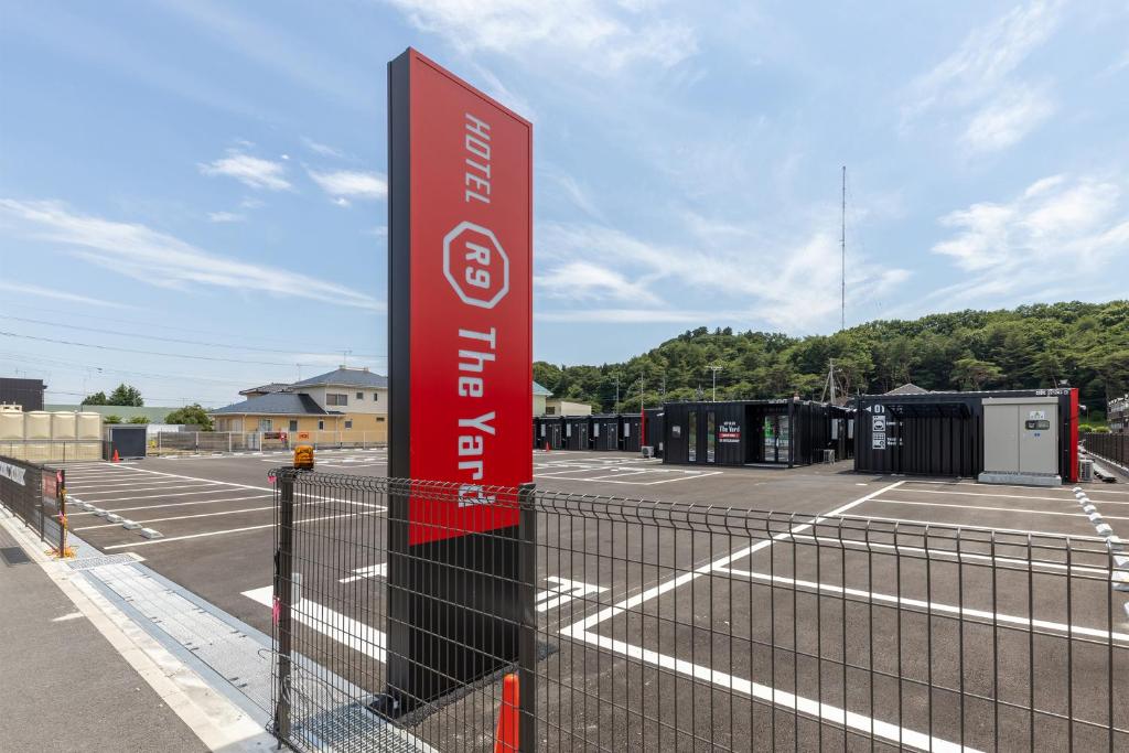 Un cartel en un estacionamiento con cancha de tenis. en HOTEL R9 The Yard Nasushiobara, en Nasushiobara