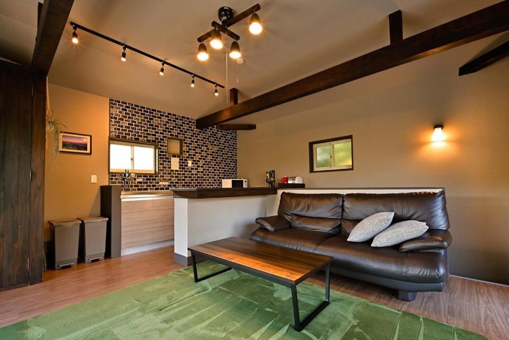 a living room with a leather couch and a table at Green Room - グリーンルーム志摩 in Shima