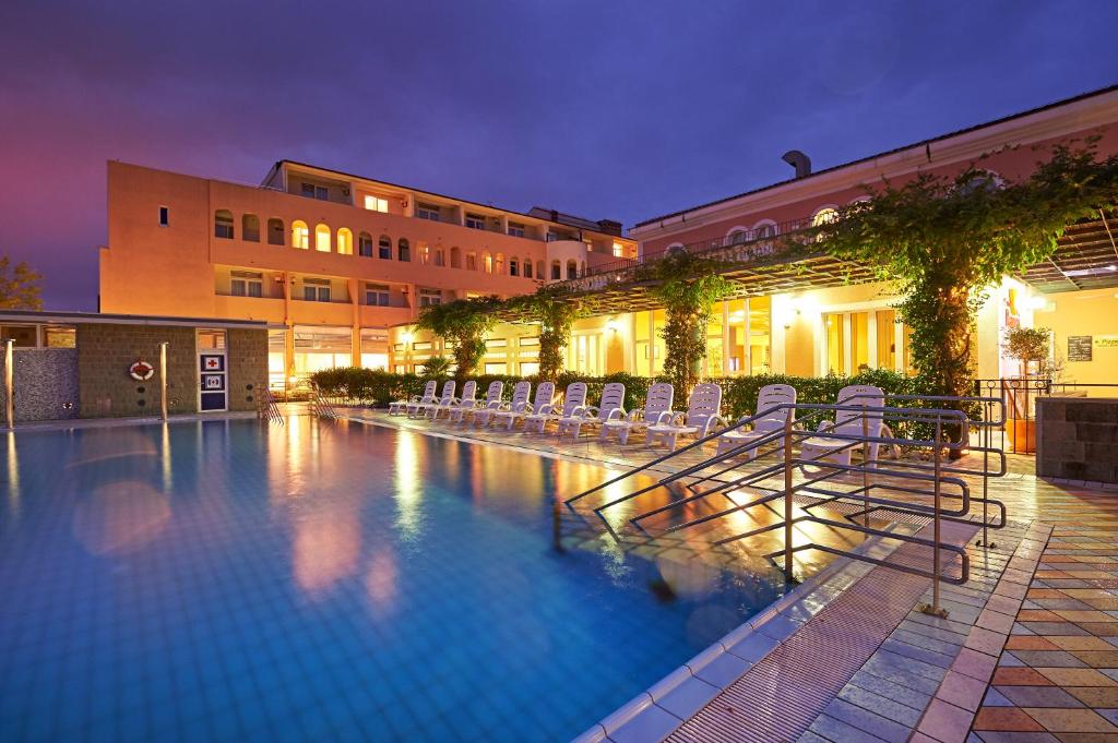 een groot zwembad met stoelen en een gebouw bij Hotel Delfin in Izola