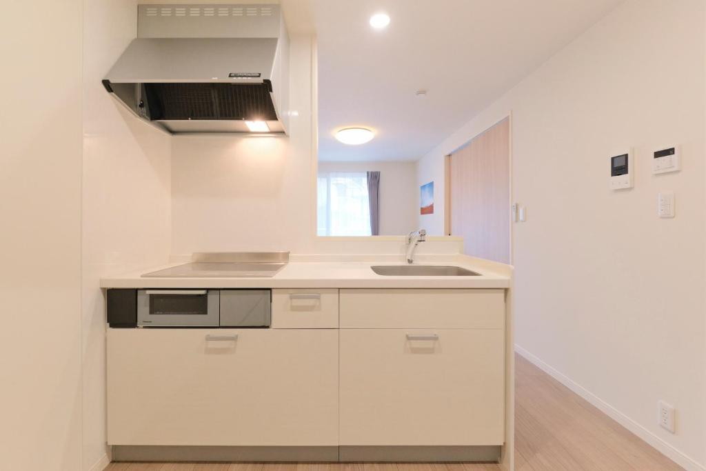 eine Küche mit weißen Schränken und einer Spüle in der Unterkunft Victoria 下北沢 by Tranova in Tokio