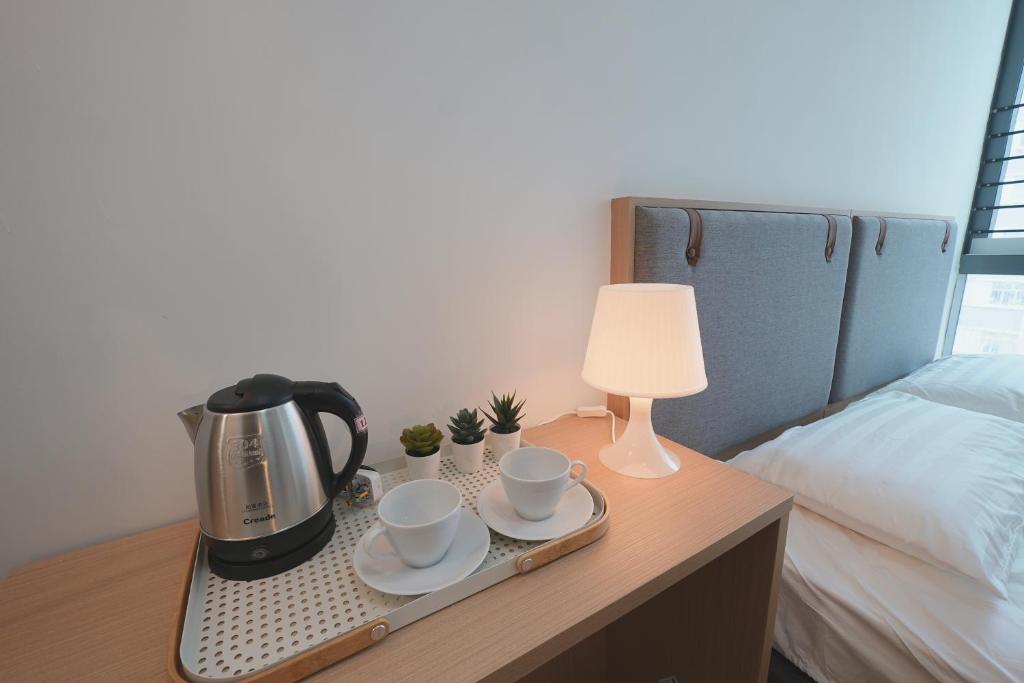 un vassoio con tazze e tazzine su un tavolo accanto a un letto di China Rich Oriental Hotel a Hong Kong