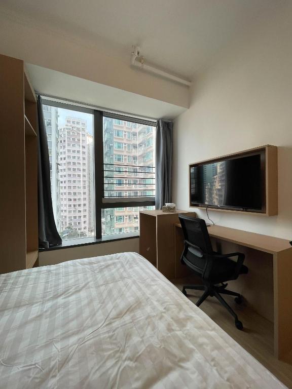 una camera con letto, scrivania e TV di China Rich Oriental Hotel a Hong Kong