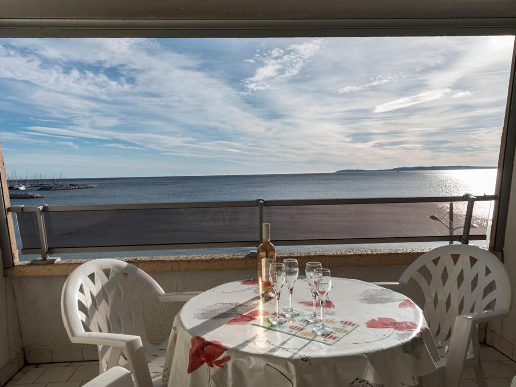 - une table avec des verres à vin sur un balcon avec vue sur l'océan dans l'établissement Studio face mer avec terrasse - 2 pers, parking, plage et centre ville à pied - FR-1-803-67, au Lavandou