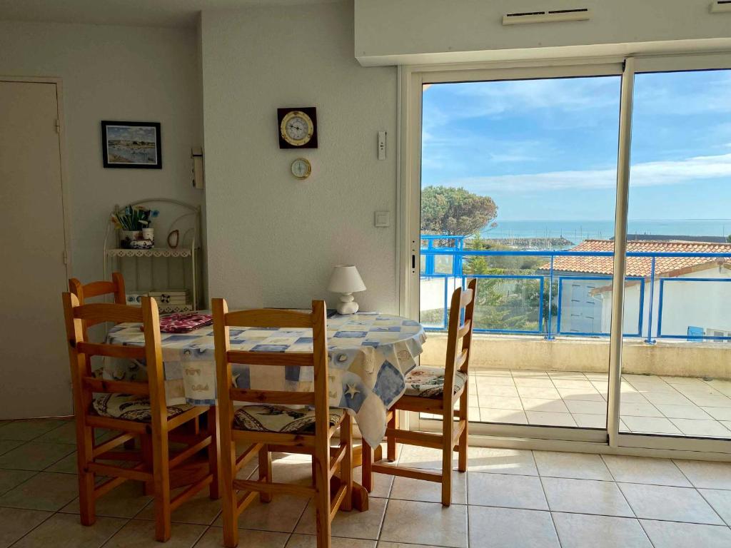une salle à manger avec une table et des chaises et un balcon dans l'établissement Appartement lumineux avec balcon et parking face au port, proche océan - FR-1-336-160, à Jard-sur-Mer