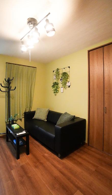 a living room with a black couch and a table at HANASTAY花渓居 椿Tsubaki in Osaka