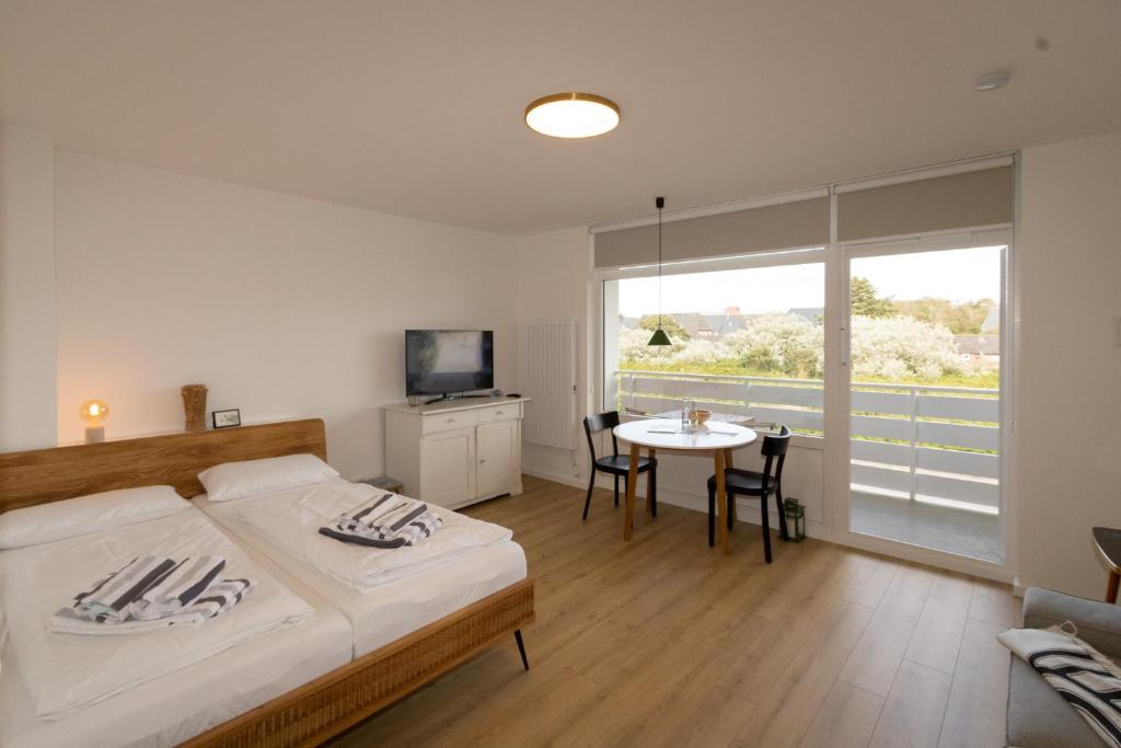 a bedroom with a bed and a table and a tv at Sylt for Friends in Hörnum