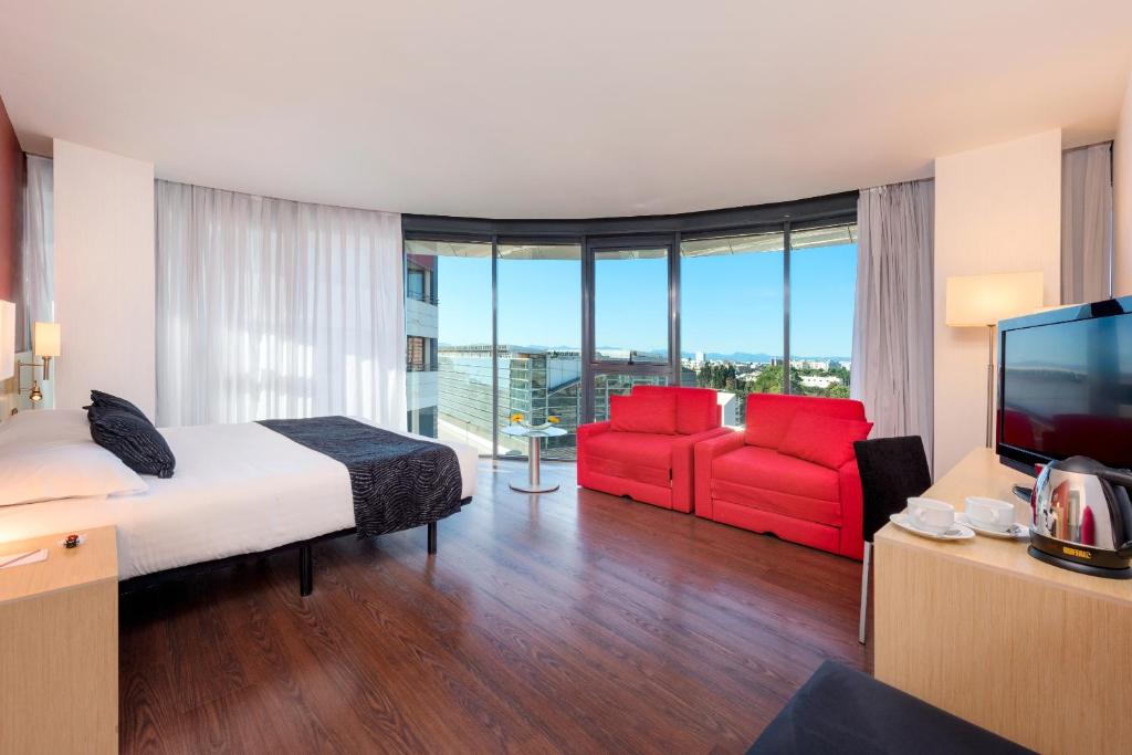um quarto de hotel com uma cama e duas cadeiras vermelhas em Civis Luz Castellón 4*S em Castellón de la Plana