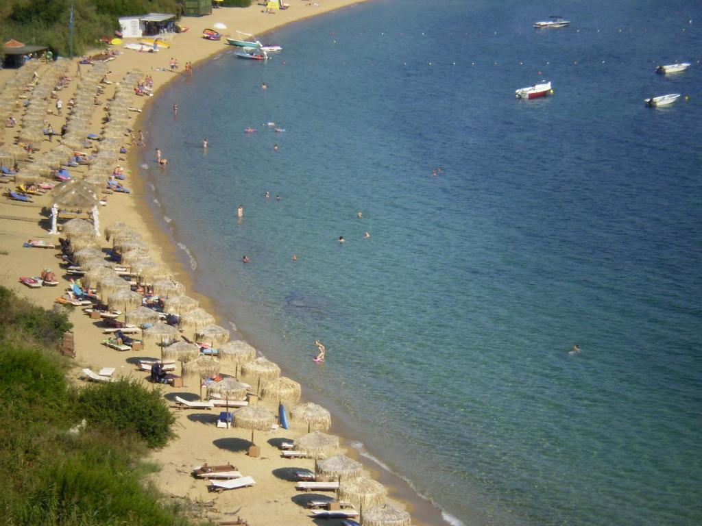 a beach with many people and umbrellas and the water at Villa Anna Maria in Agia Paraskevi