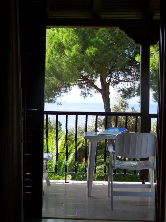 a table and chairs on a porch with a view of the ocean at Villa Anna Maria in Agia Paraskevi
