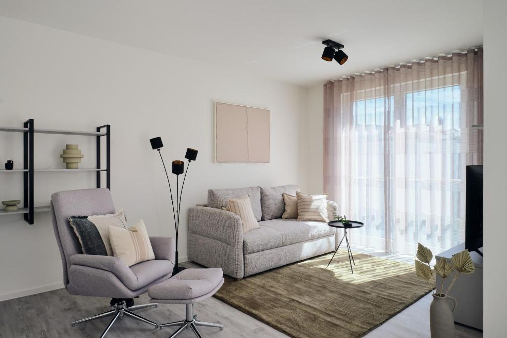 a living room with a couch and a chair at Apartment A12 - zwei Bäder, Balkon & Nutzung der Gemeinschaftsräume im "Pine Hill Resort" in Zirchow