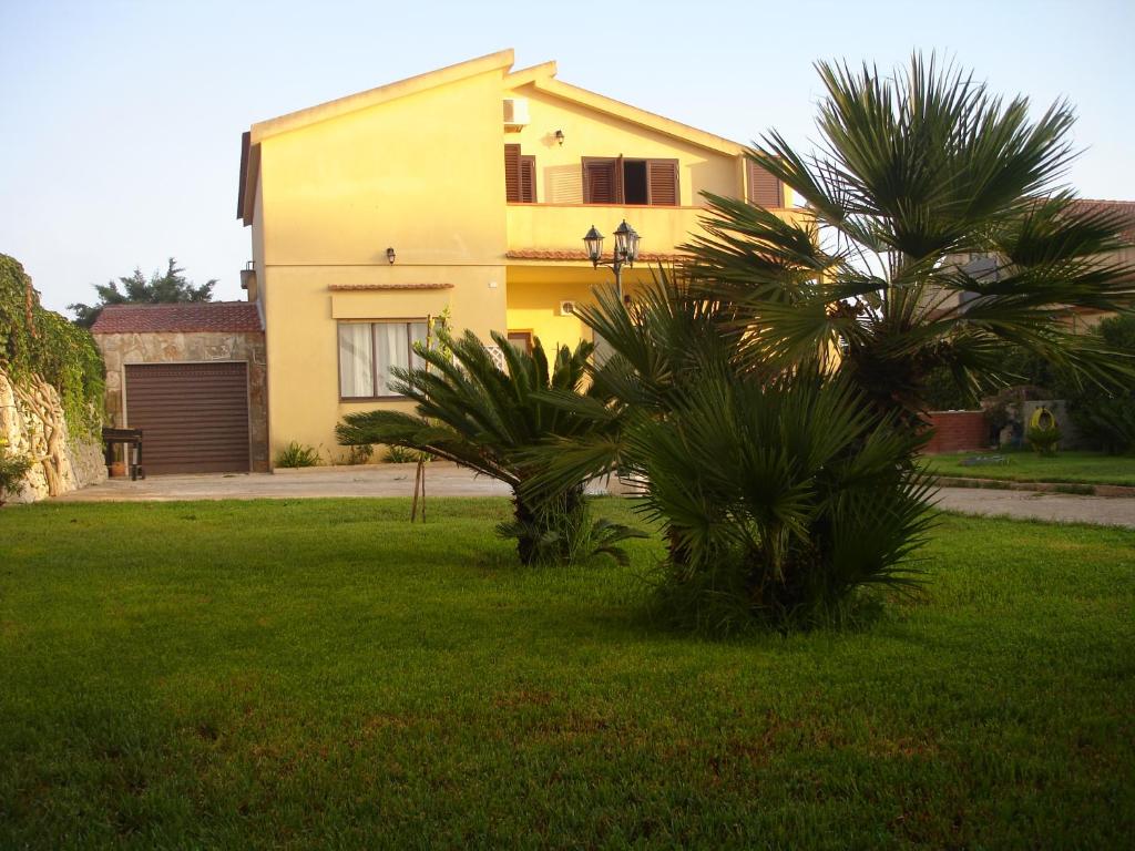 una casa amarilla con una palmera en un patio en Ulivo Apartment, en Ragusa