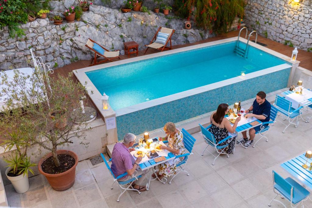 a group of people sitting at tables by a pool at Boutique Hotel Capitano in Herceg-Novi
