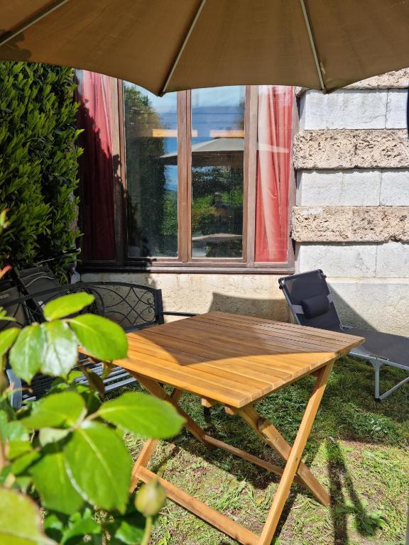 - une table de pique-nique en bois avec un parasol dans la cour dans l'établissement Château d'Uriage - Duplex avec terrasse privative, à Saint-Martin-dʼUriage